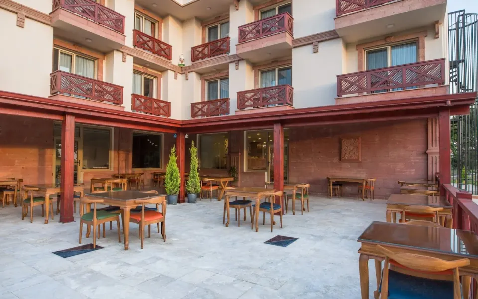 Otel Teras Restoranı – Ahşap Masa ve Renkli Minderli Sandalye