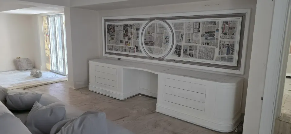 Tadilattaki villa odasında beyaz lake çekmeceli konsol ve gazeteyle korunan duvar paneli