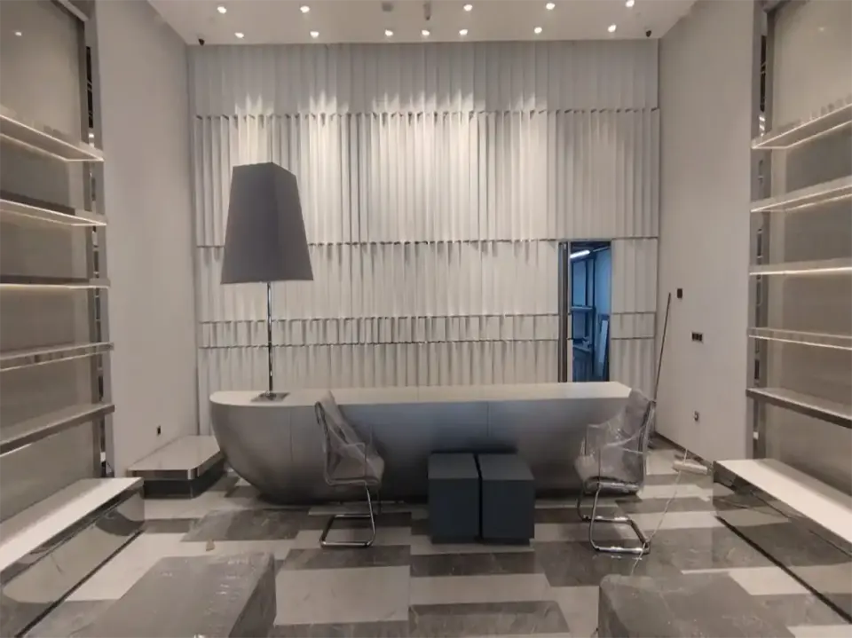 Boat-shaped grey counter in front of wavy white wall panels in a store interior