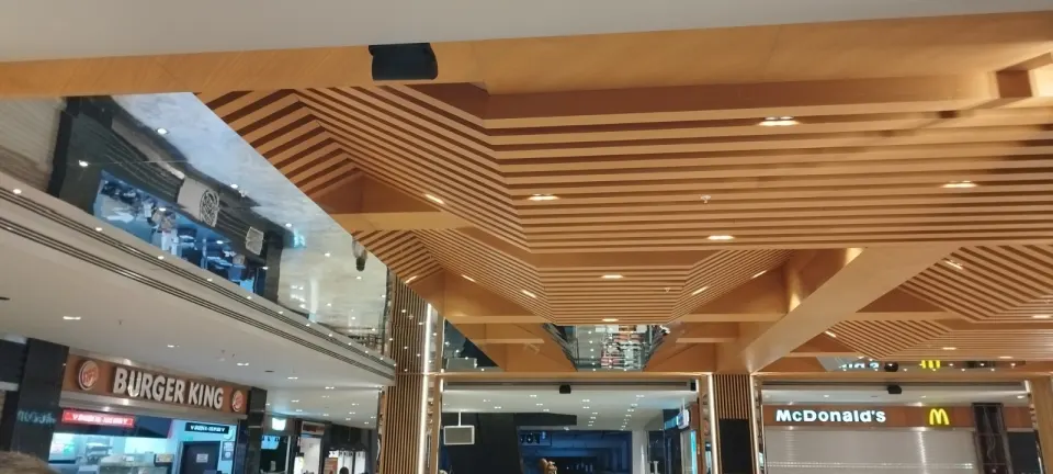 Restoran dükkanlarının üzerinde köşeli desen oluşturan ahşap çıtalı asma tavan
