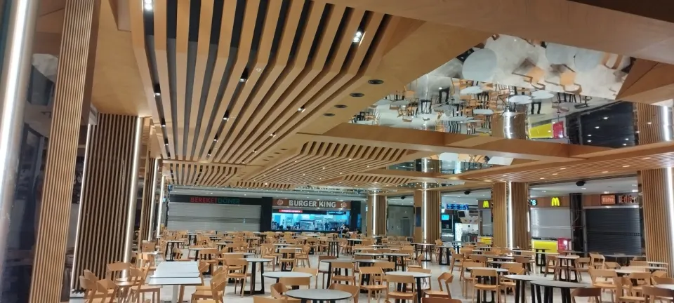 Yemek katında ahşap çıtalı tavanın aynalı yüzeyle birleştiği bölüm ve sıralı masalar