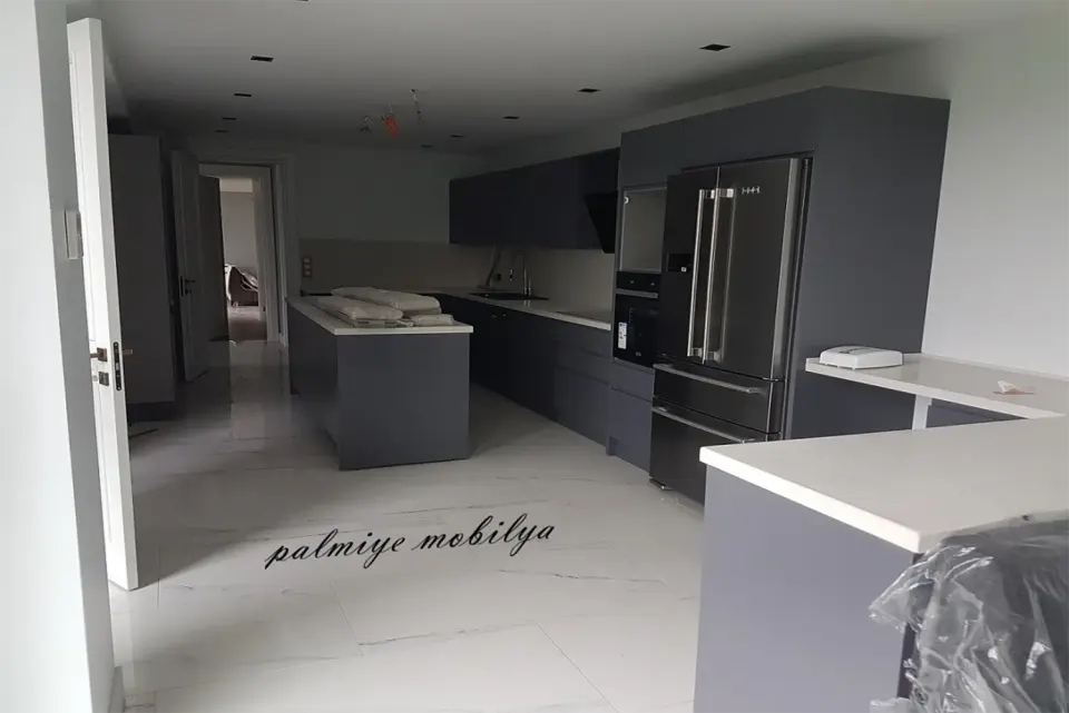 Antrasit kapaklı mutfakta beyaz tezgahlı ada ve ankastre buzdolabı